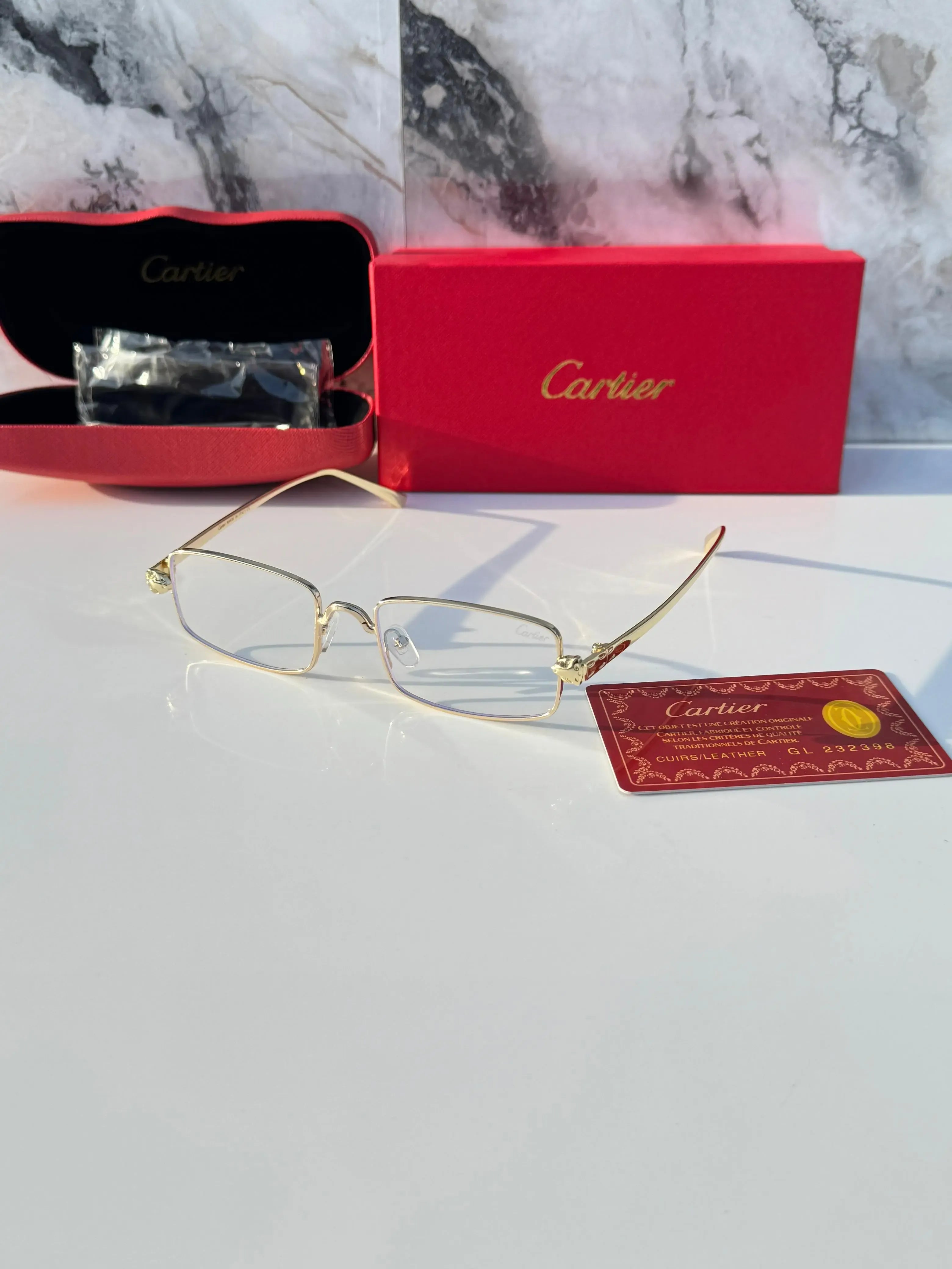 Gold rectangular eyeglasses with clear lenses - flat lay with Cartier card