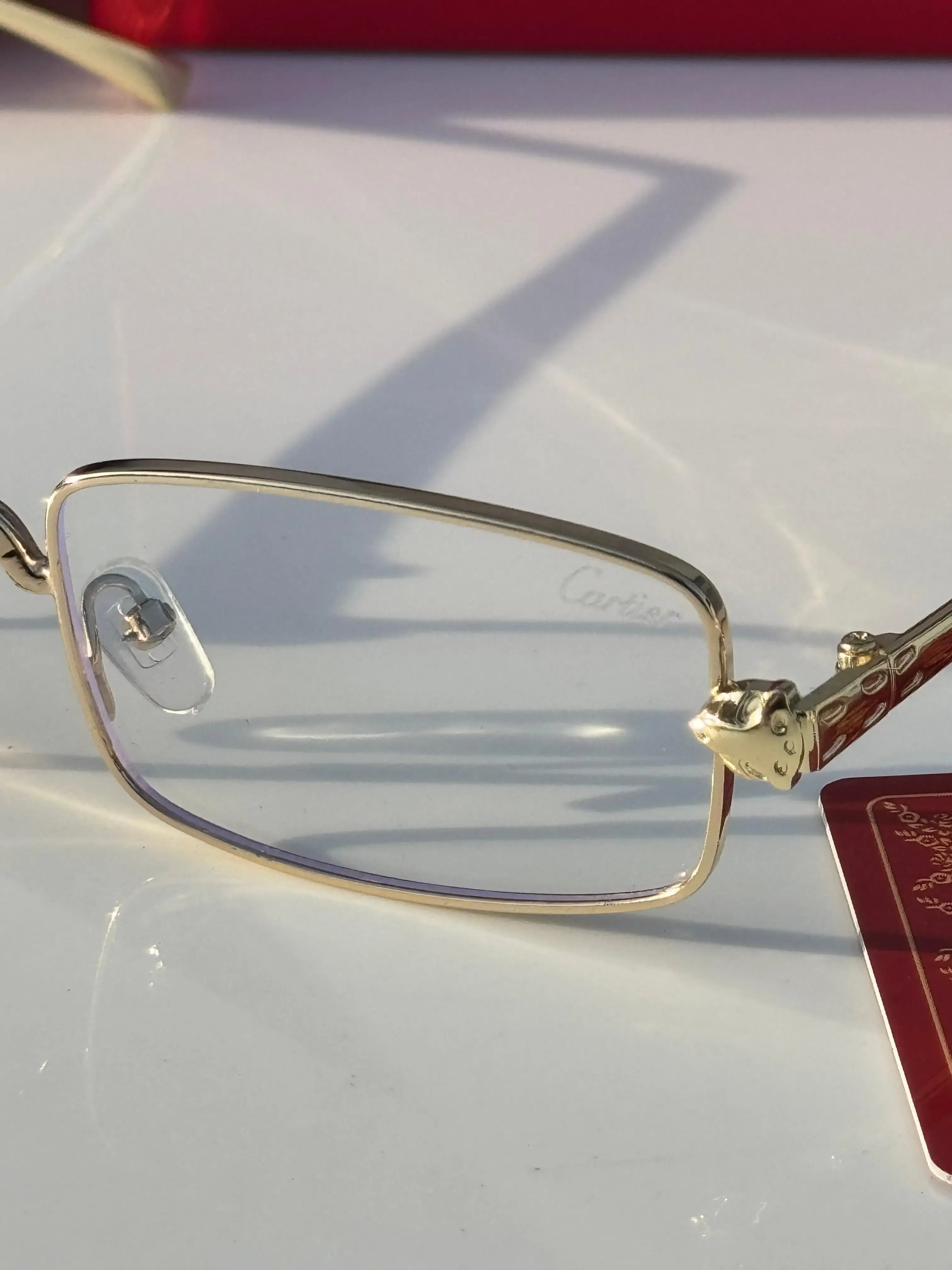 Gold rectangular eyeglasses - front view on marble surface