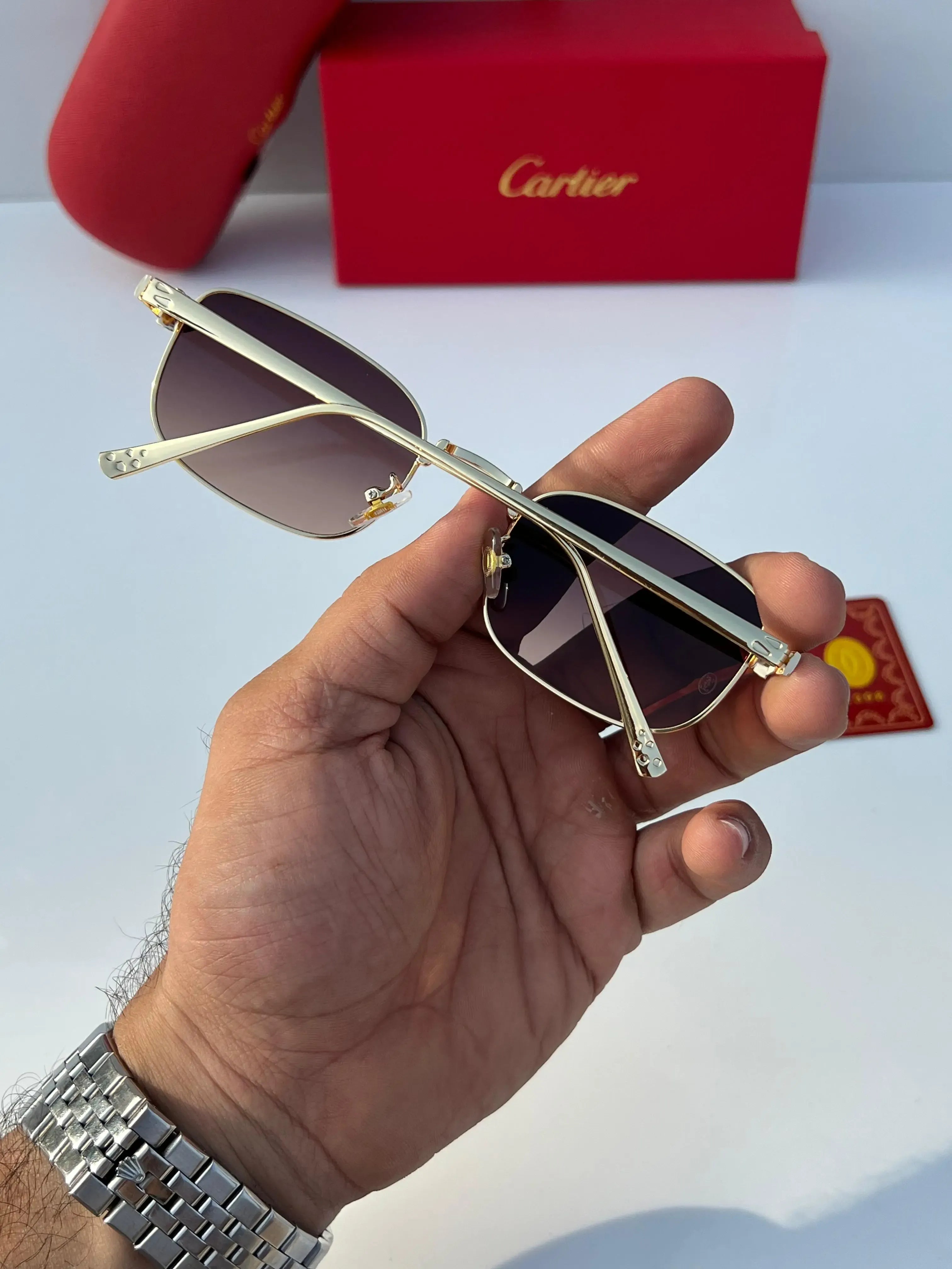Gold rectangular sunglasses with brown gradient lenses - close up of sculpted panther hinge and Cartier branding on lens