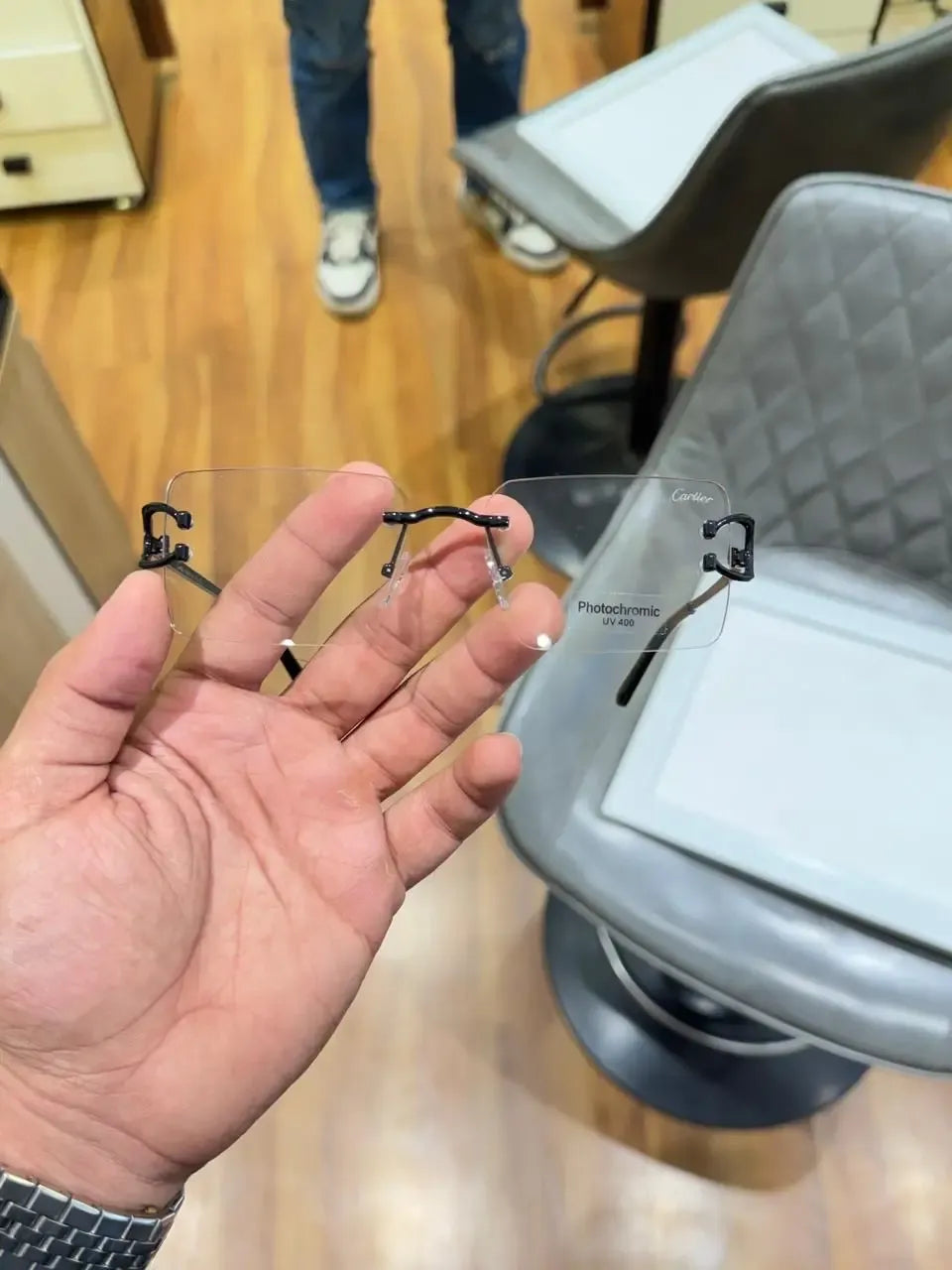 Rimless black C-frame eyeglasses - palm view showing full frame and photochromic lenses
