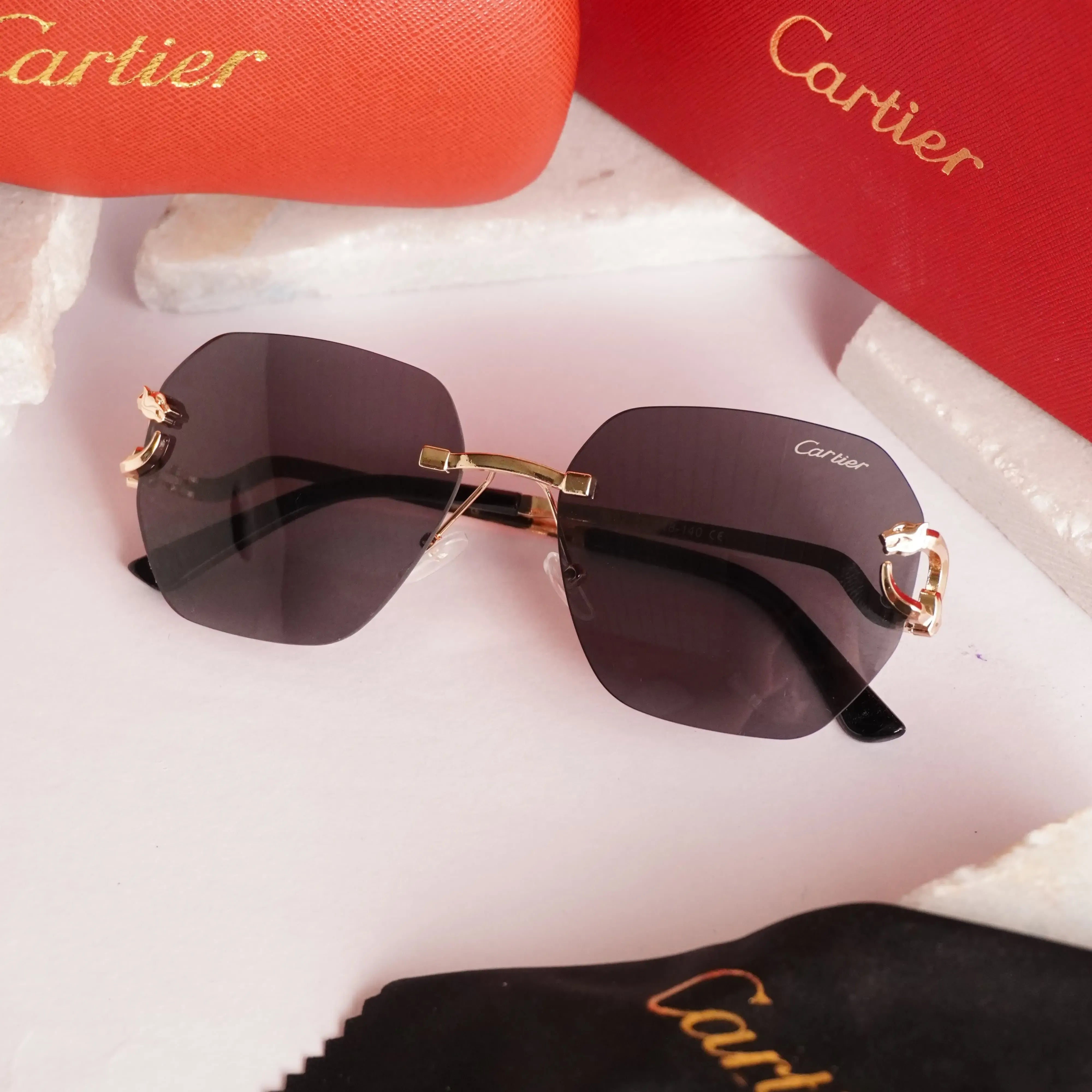 Rimless gold panther black sunglasses - close up of sculpted gold panther hinge with red enamel