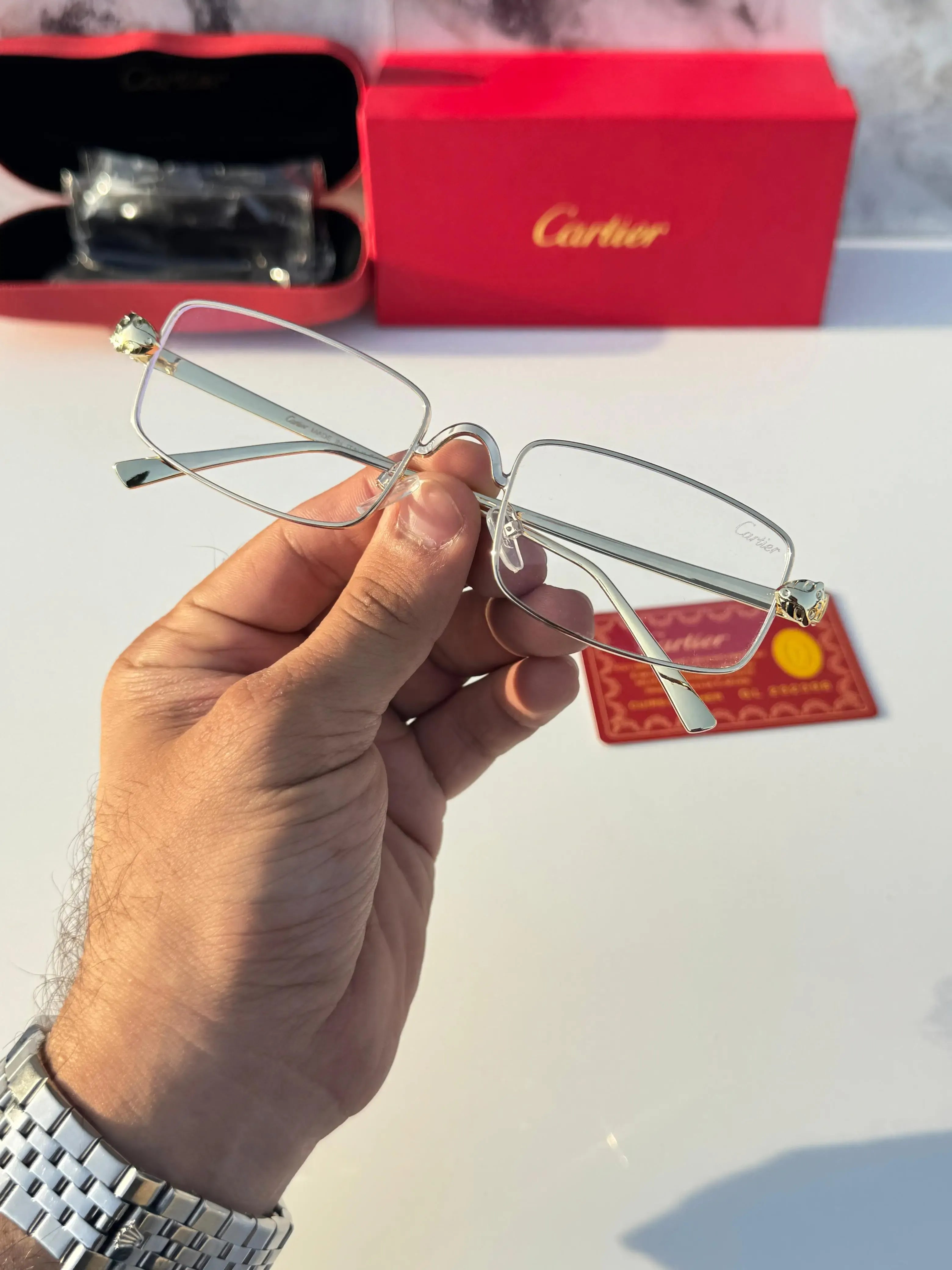 Gold rectangular eyeglasses - held in hand showing temple detail