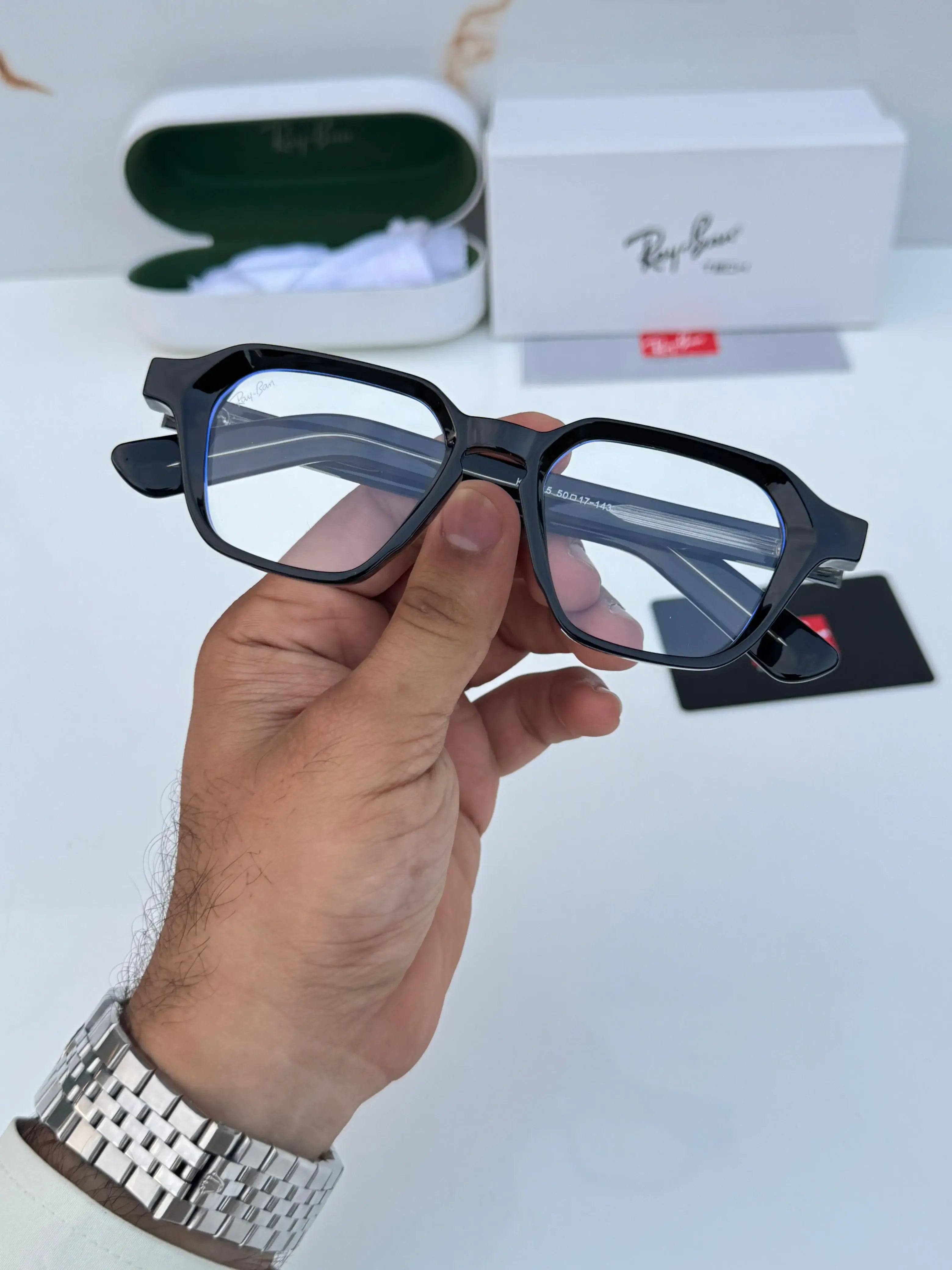 Ray-Ban RB1115 Black Plano - Hand holding folded frame showing temple arms with silver rivet detail