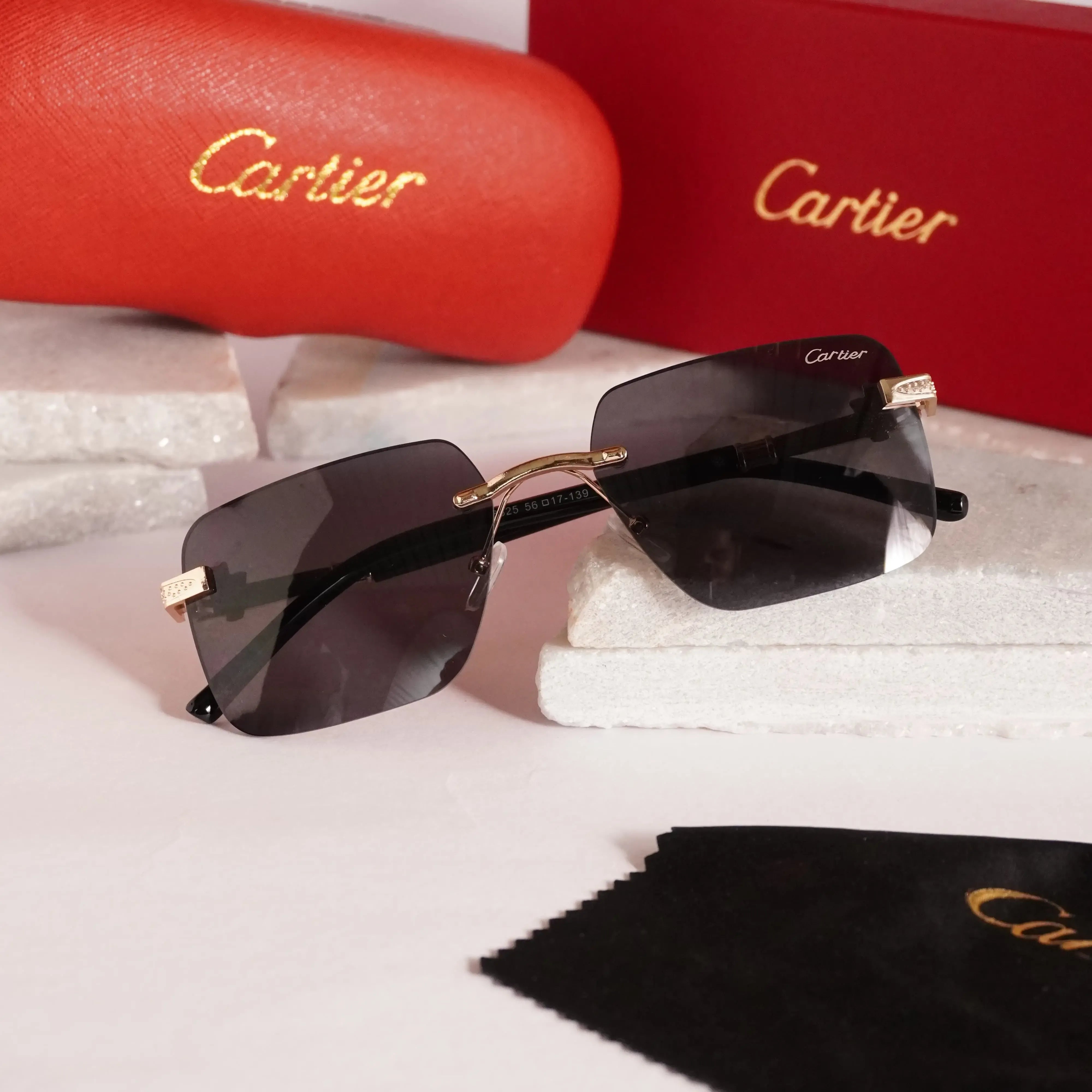 Rimless square gold black sunglasses - side angle showing dark lenses and gold bridge with Cartier box