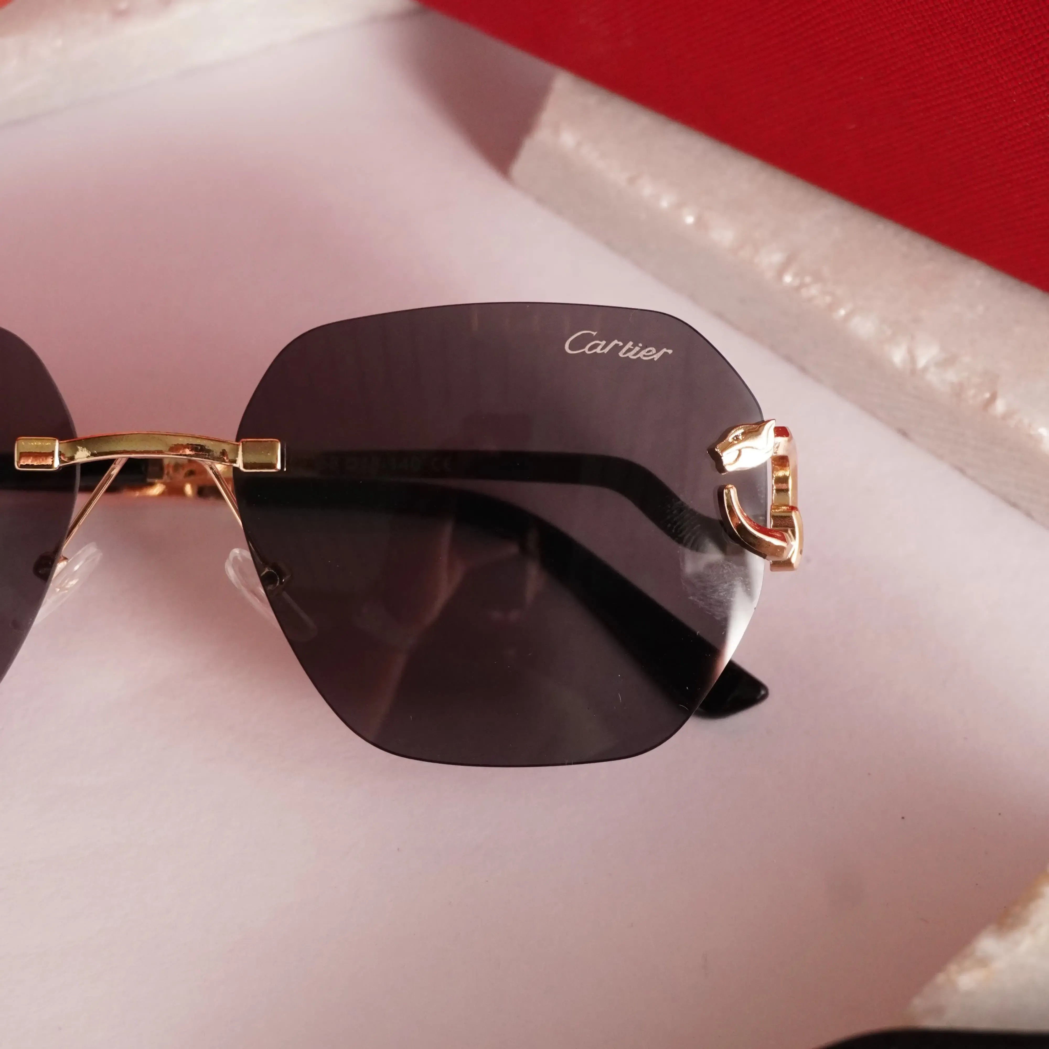 Rimless gold panther black sunglasses - flat lay top view with Cartier cleaning cloth