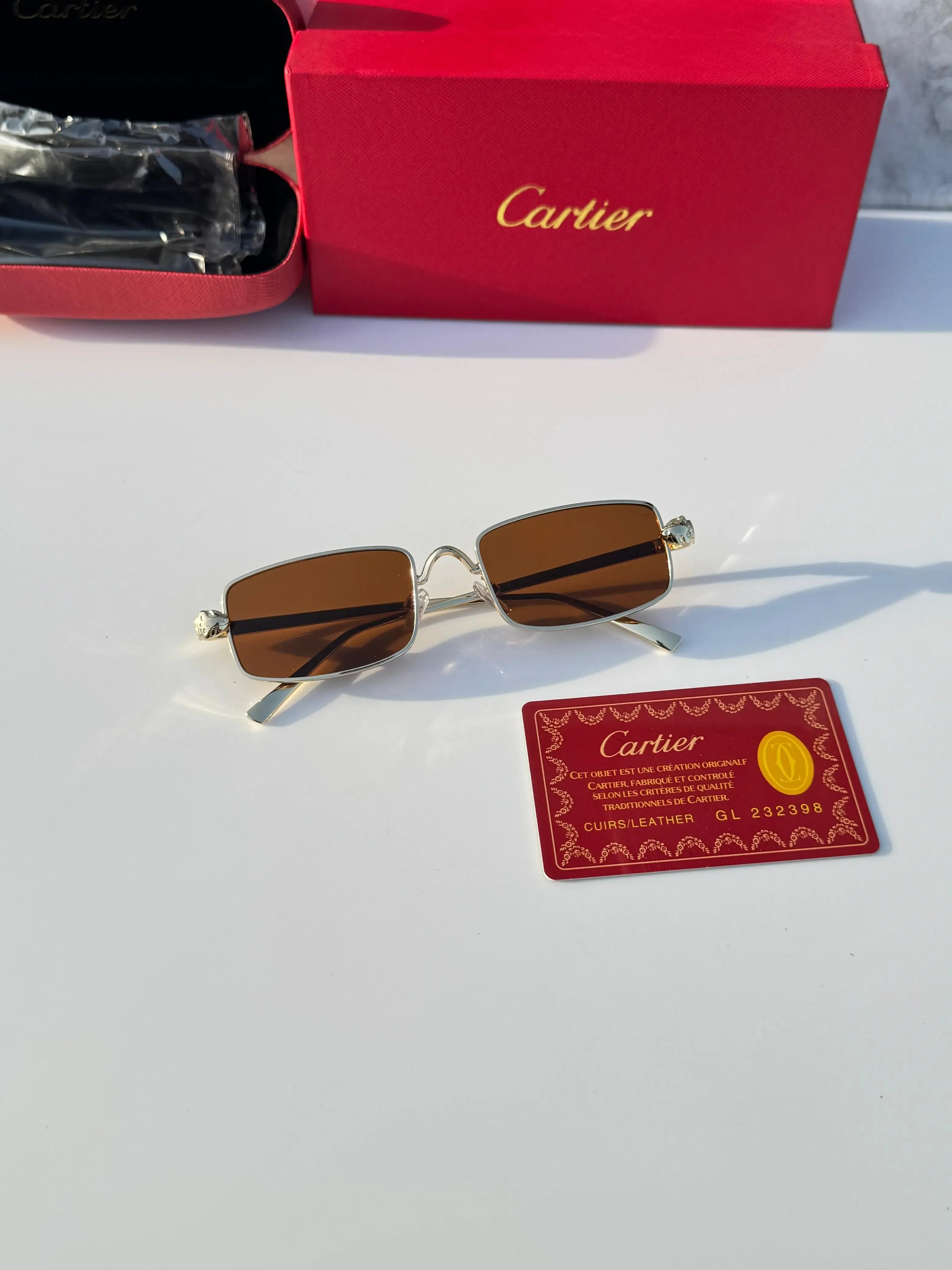 Gold rectangular sunglasses with brown lenses - held in hand showing side profile and gold temples