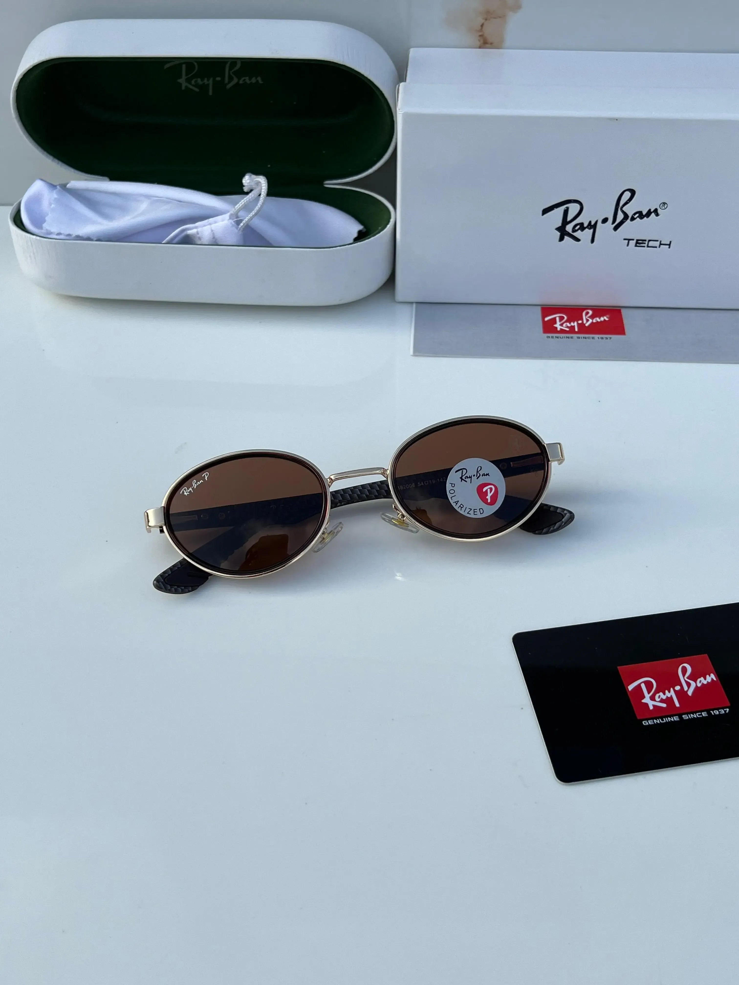 Ray-Ban x Ferrari RB8206 Gold Brown - Hand holding folded frame showing carbon fibre temple arms and gold oval frame