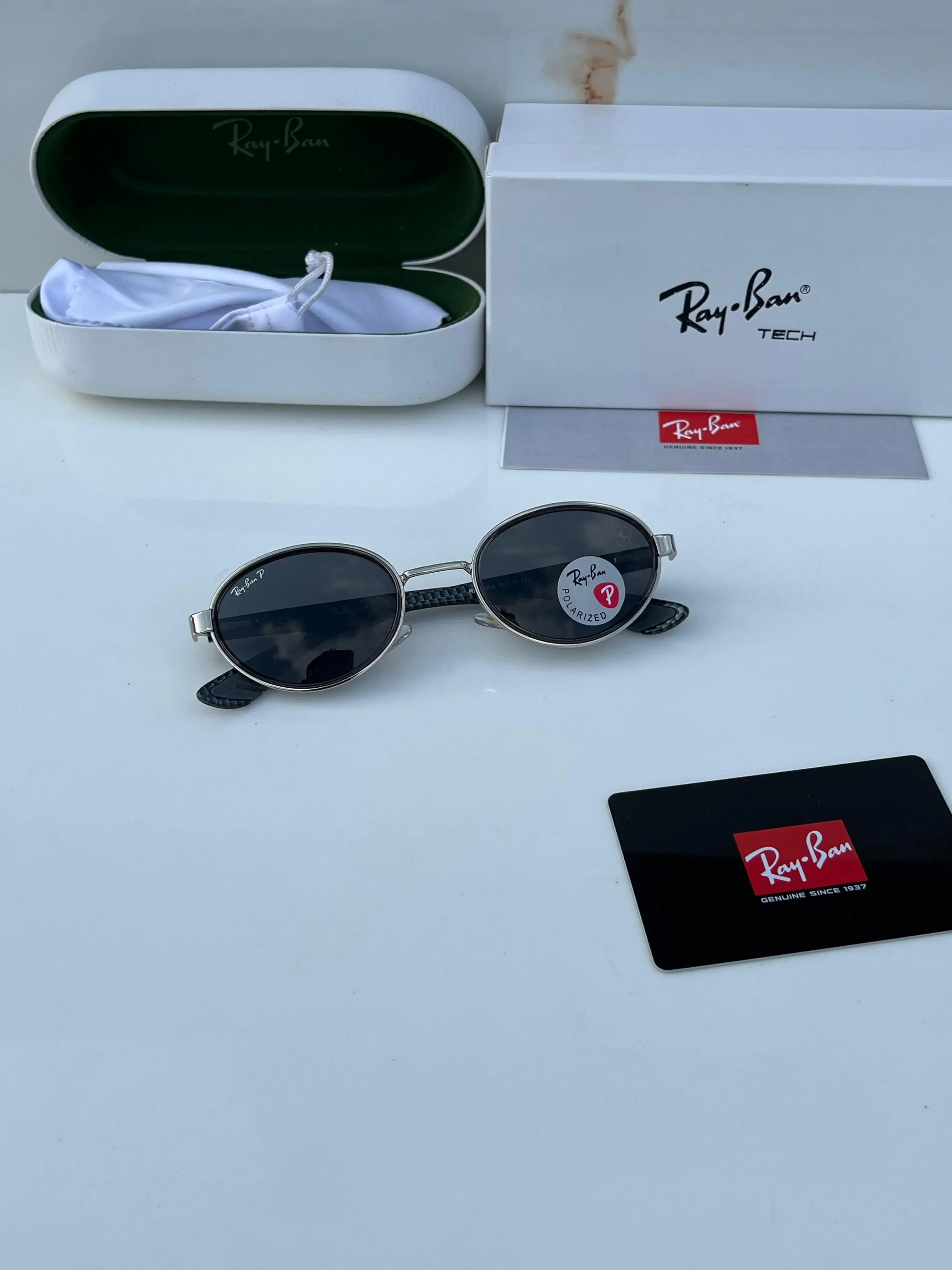 Ray-Ban x Ferrari RB8206 Silver Black - Close-up showing silver oval rim, dark grey polarized lens, carbon fibre arms and Ferrari Prancing Horse badge